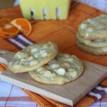Orange creamsicle cookies with white chocolate chips on a wooden board