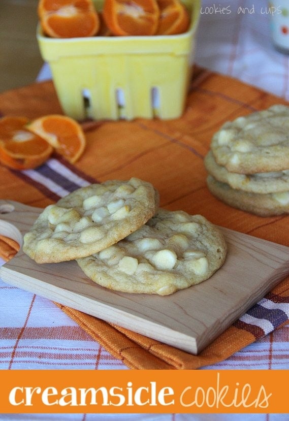 Orange creamsicle cookies with white chocolate chips on a wooden board