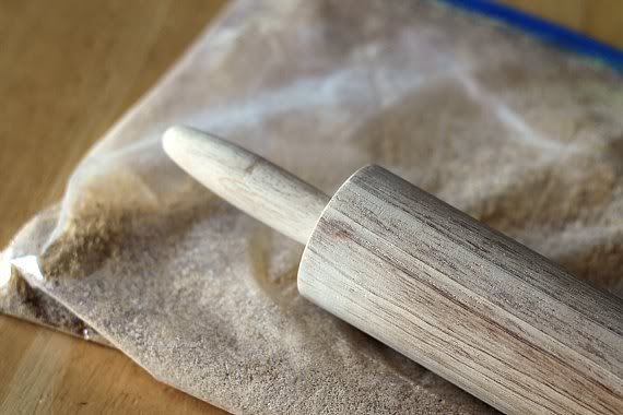 A ziploc bag of graham cracker crumbs with a rolling pin
