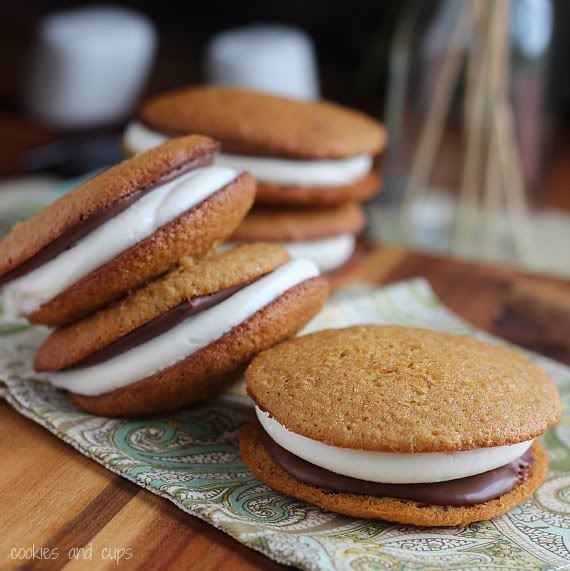 Several S'mores Whoopie Pies with chocolate and marshmallow filling on a tea towel