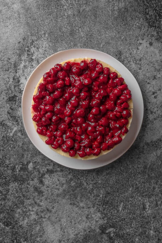 Overhead view of cheesecake topped with cherry pie filling.