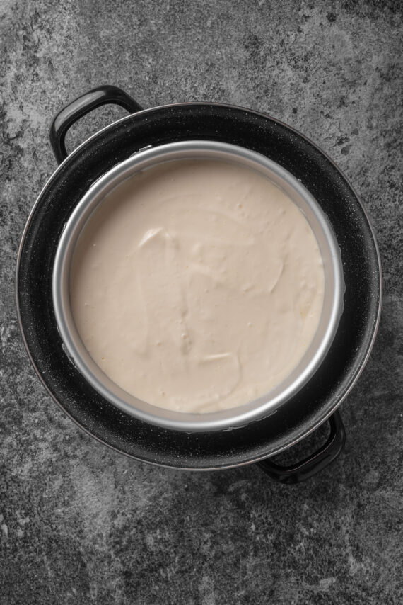 Cheesecake batter in a springform pan placed inside a larger pan with a water bath.