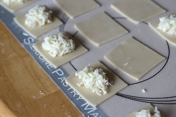 Squares of dough with a scoop of coconut filling in the middle