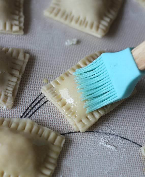 Pastry brush spreading egg wash over dough squares