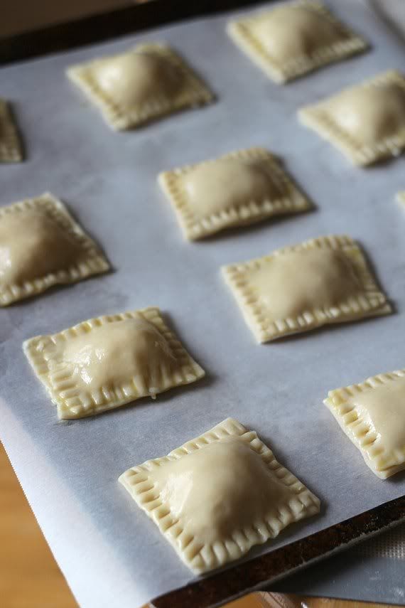 Filled dough squares on a parchment-lined baking sheet