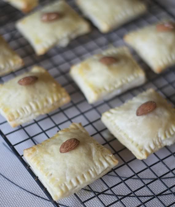 Pastry squares topped with an almond on a cooling rack