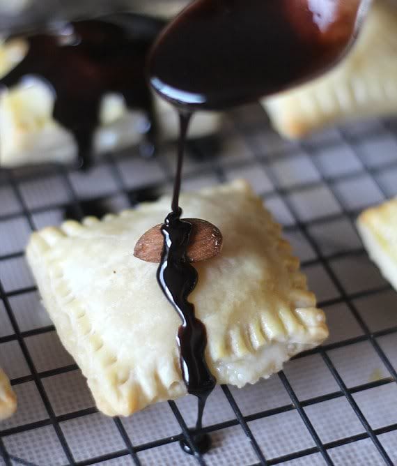 Chocolate being drizzled over pastry squares on a cooling rack