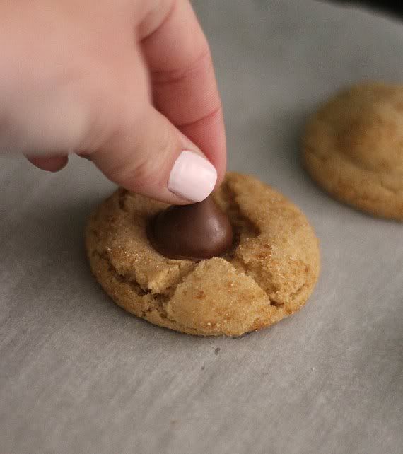 A Hershey's kiss being pressed into a peanut butter cookie