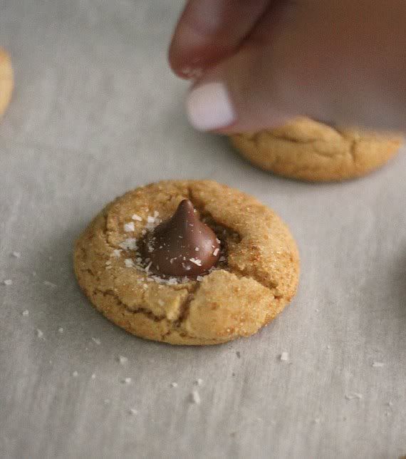 Peanut butter cookie with a Hershey kiss being sprinkled with sea salt