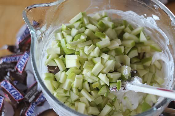 Chopped green apple added to a mixing bowl of cream cheese and whipped topping