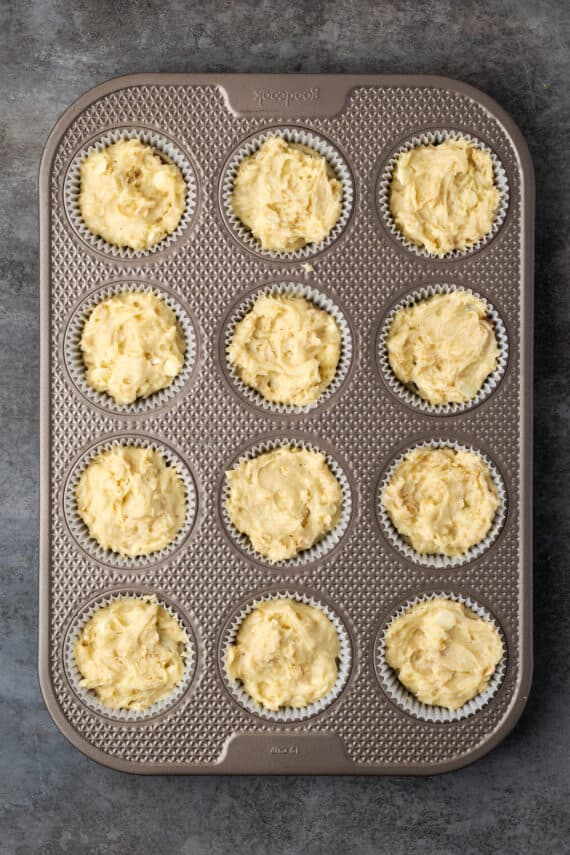 Unbaked cinnamon muffin batter in a 12-well muffin pan.