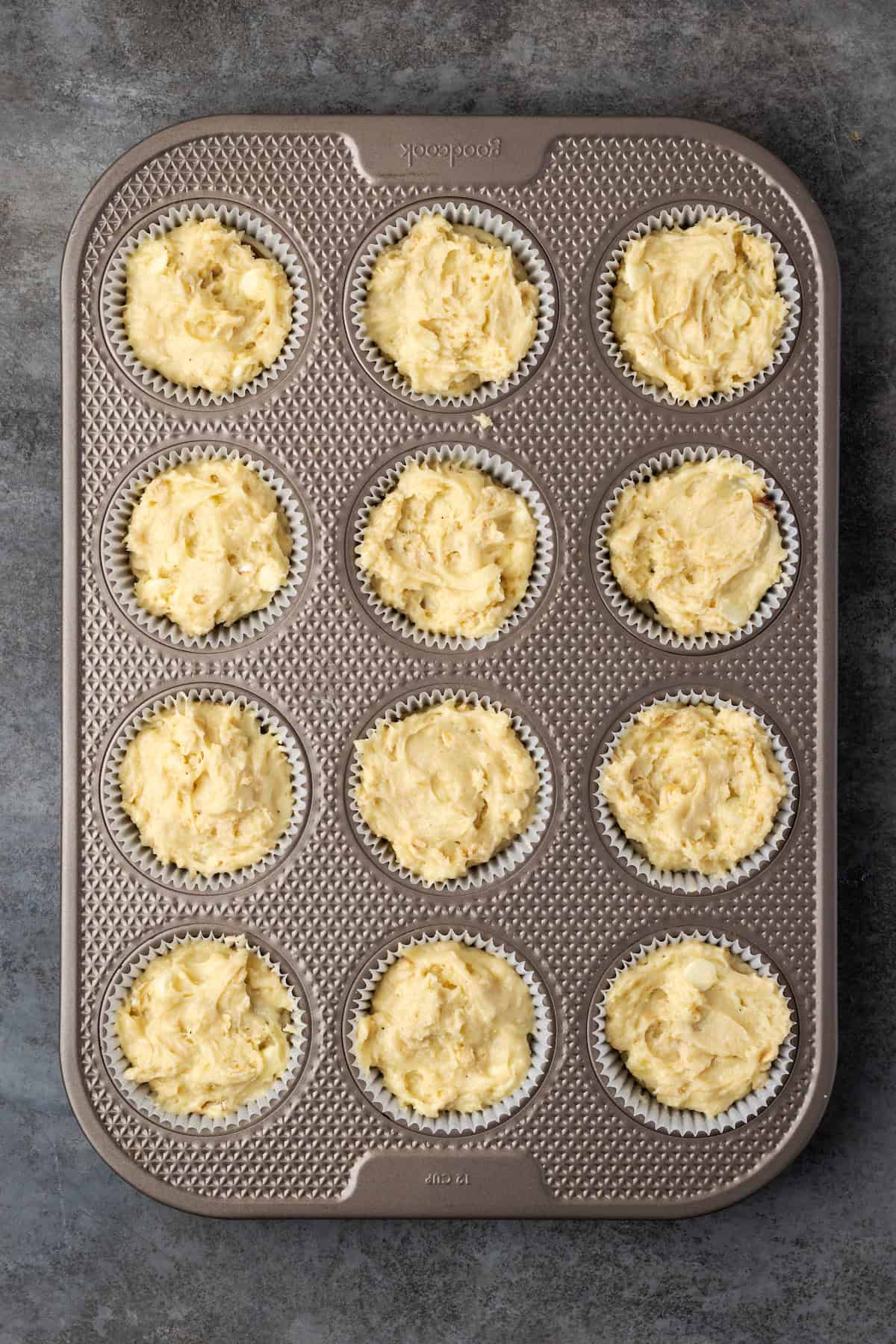 Unbaked cinnamon muffin batter in a 12-well muffin pan.