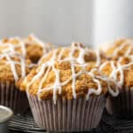 Cinnamon muffins on a wire rack drizzled with glaze.