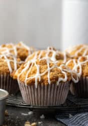 Cinnamon muffins on a wire rack drizzled with glaze.