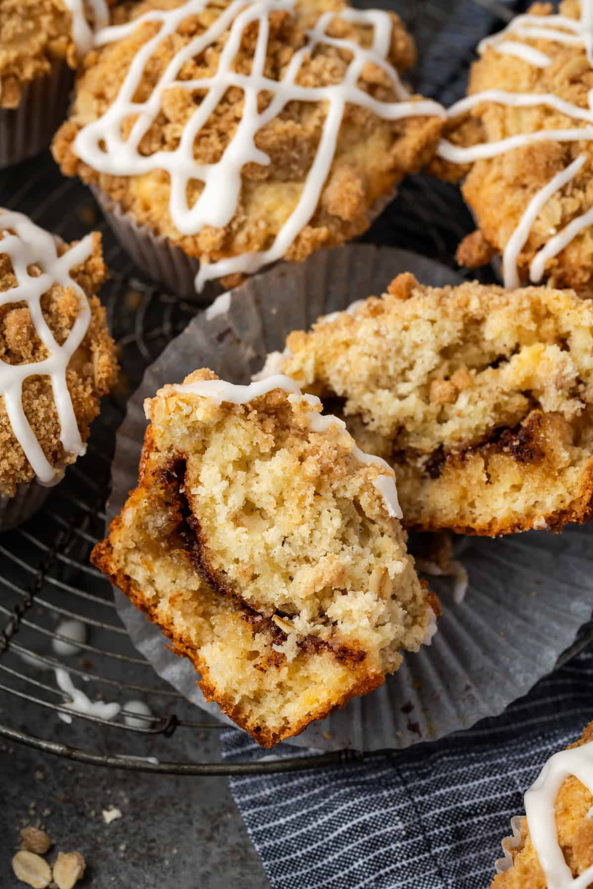 A cinnamon muffin cut in half to reveal the cinnamon filling, surrounded by more muffins in the wells of a muffin tin.