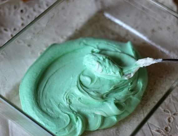 Green colored fudge being spread in a square pan