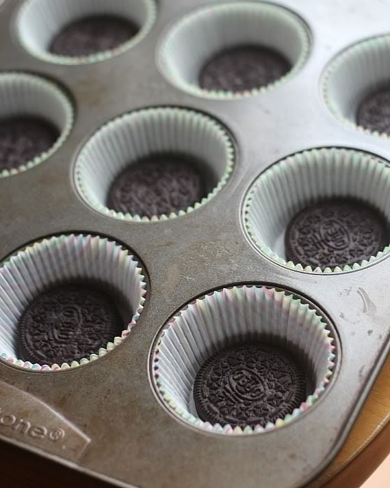 A paper-lined muffin tin with an oreo cookie in each cup