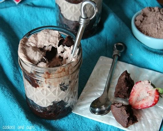Brownie batter parfait in a jar with brownie pieces and a strawberry next to it
