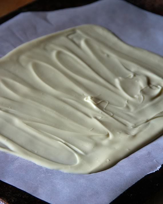 Melted white chocolate spread on a parchment-lined baking sheet