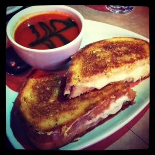 Grilled cheese on a plate with a cup of tomato soup