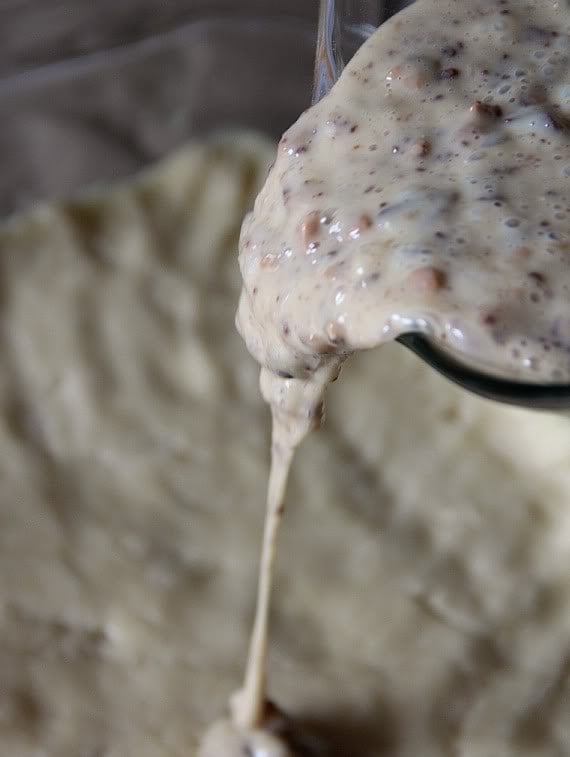 Batter with toffee pieces being poured over crust in a baking dish