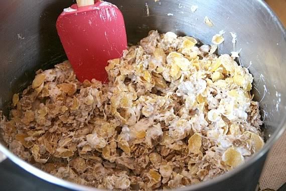 Honey Bunches of Oats cereal in a mixing bowl with melted butter and marshmallows