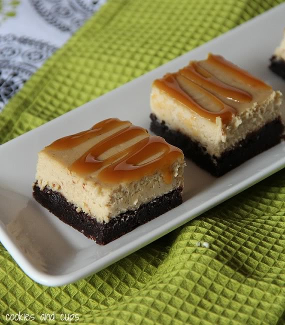 Brownie bottom cheesecake bars on a plate with caramel drizzle