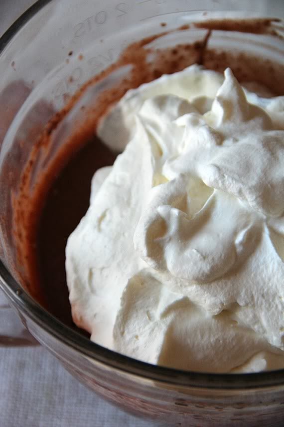 Whipped cream being added to a bowl of liquid chocolate mixture