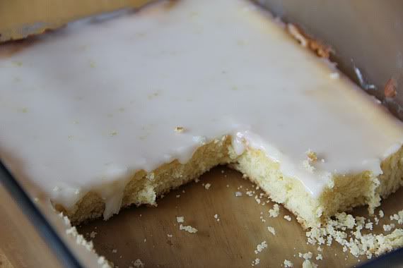 Glazed lemon brownies in a glass baking dish, with several brownies missing.