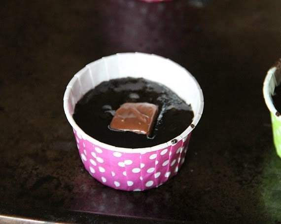 A muffin cup with chocolate cupcake batter and a mini 3 Musketeers bar