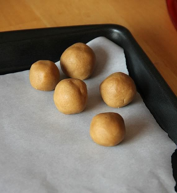 5 cookie dough balls on a parchment-lined baking sheet