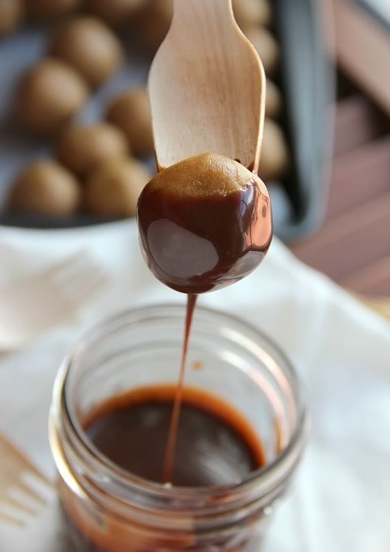 A cookie dough ball being dipped into a jar of melted chocolate