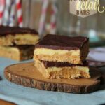 Two peanut butter eclair bars stacked on a wooden slice