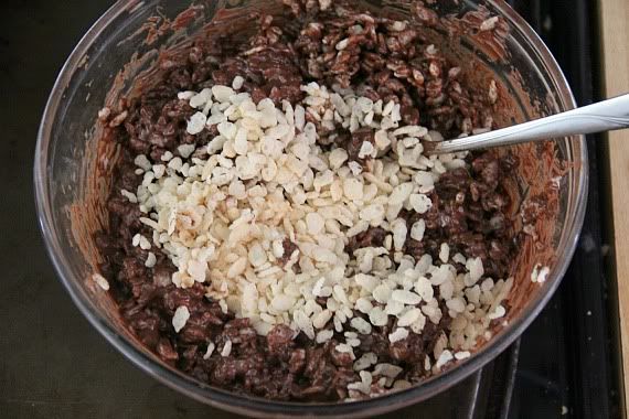 Krispie cereal added to a bowl of melted chocolate peanut butter mixture