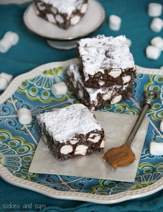 Chocolate Puppy Chow Krispie Treat squares topped with powdered sugar on a plate