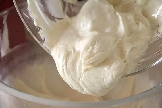 Melted white chocolate being poured into a bowl of cream cheese mixture