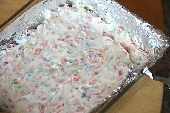 Fruity Pebbles fudge spread in a foil-lined square pan