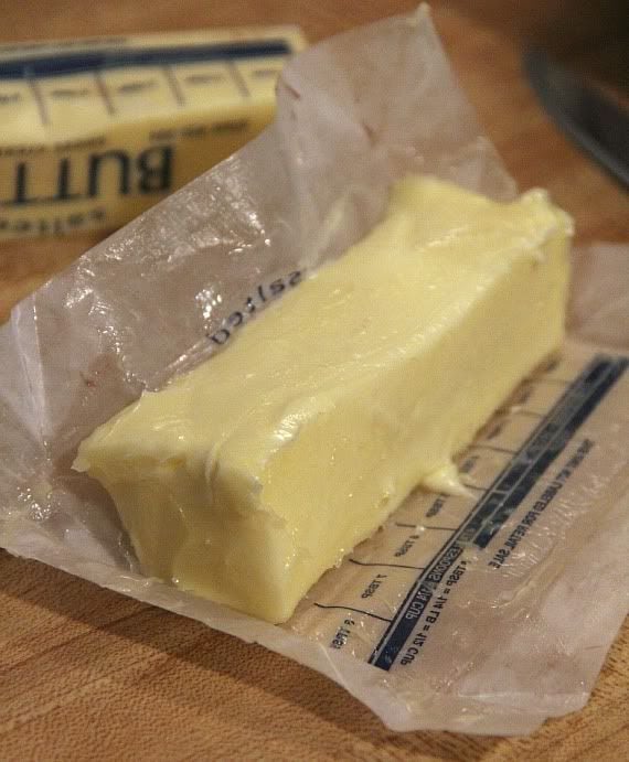 A stick of partially unwrapped softened butter