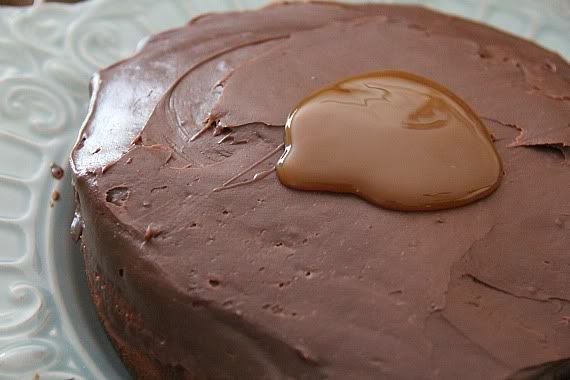 Round chocolate frosted cake with a pool of caramel sauce on top