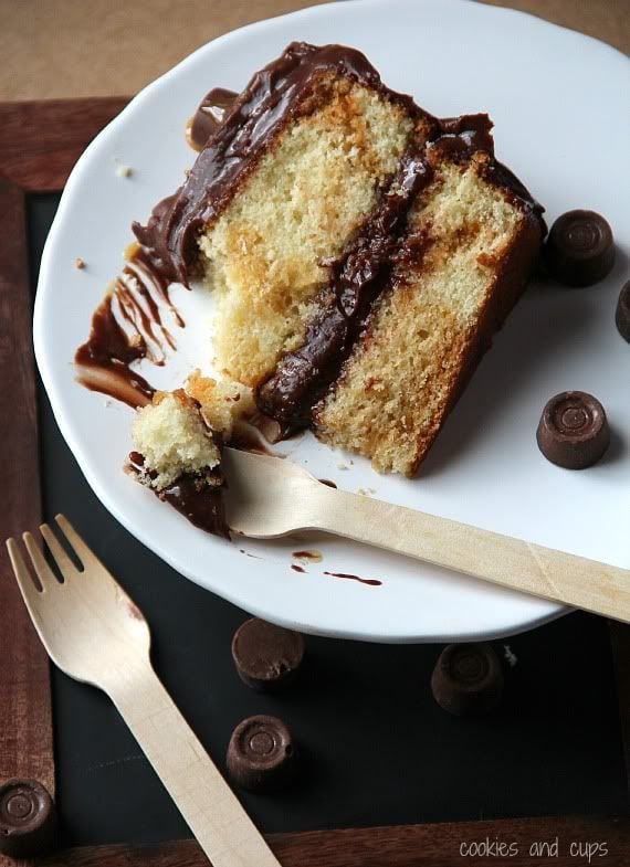 A slice of yellow cake with chocolate frosting on a plate with rolo candies