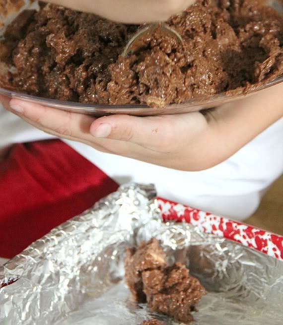 Chocolate peanut butter cookie mixture being spooned into a foil-lined pan