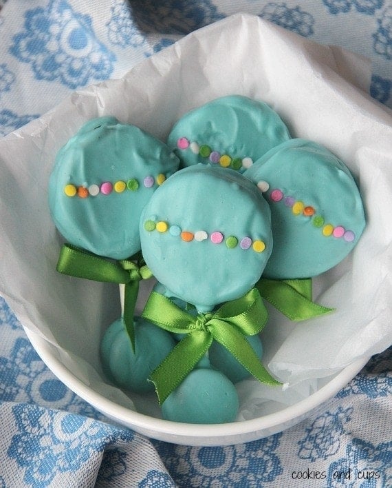 Overhead view of teal Oreo Pop baby rattles in a white bowl