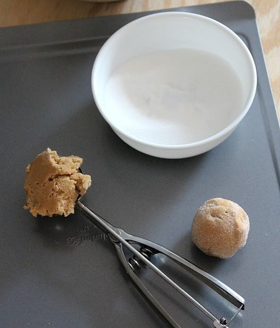 Peanut butter cookie dough ball next to a bowl of sugar