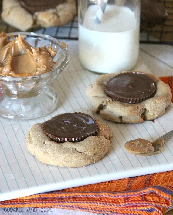 Giant Peanut Butter Blossom cookies next to a bowl of peanut butter and a glass of milk