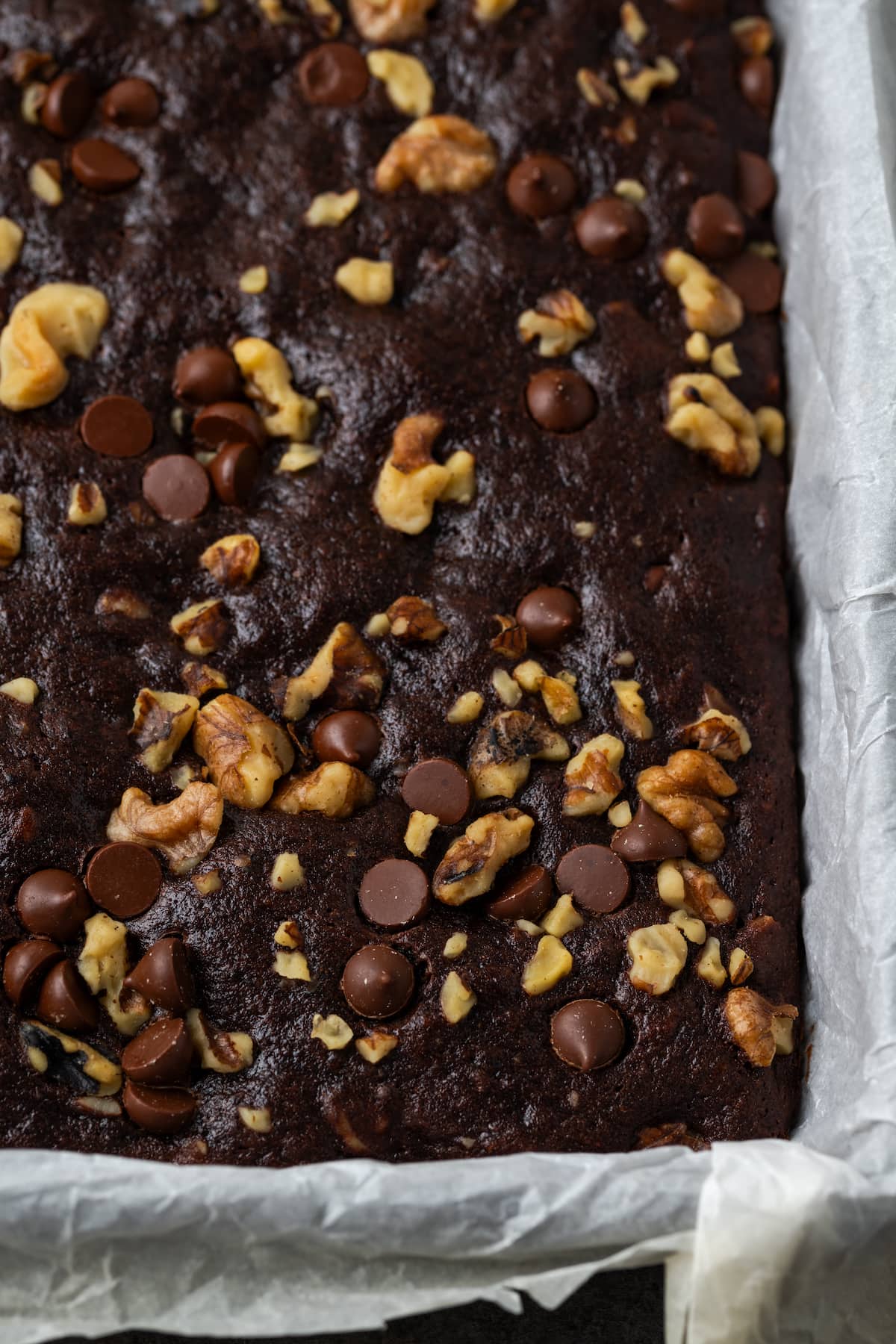 Close up of baked banana bread brownies in a parchment-lined baking pan.