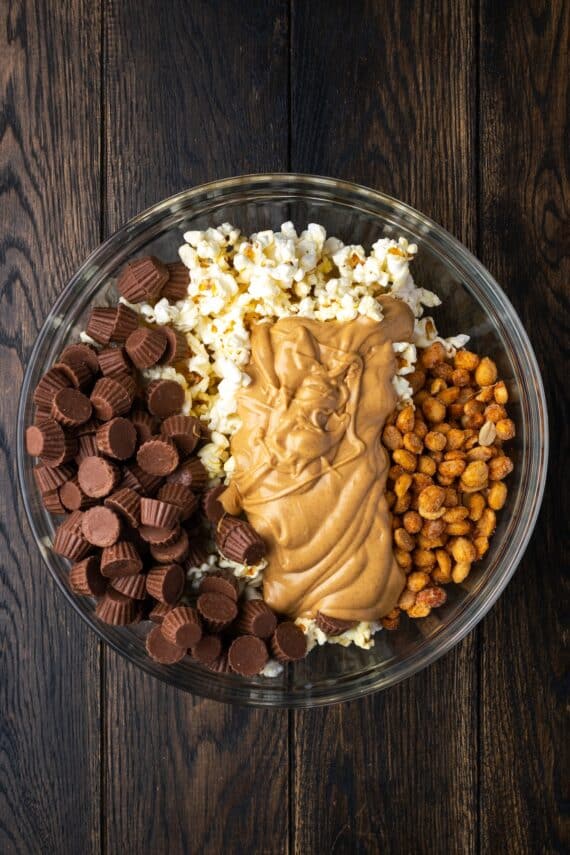 Melted peanut butter chips added to the popcorn mix in a bowl.