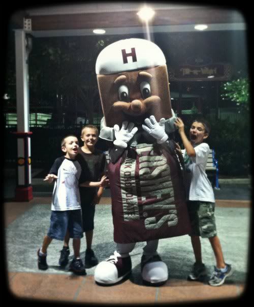 3 boys posing with a Hershey's chocolate bar mascot