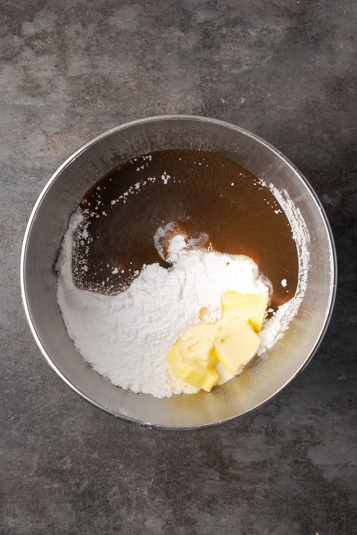 Caramel frosting ingredients combined in a metal mixing bowl.