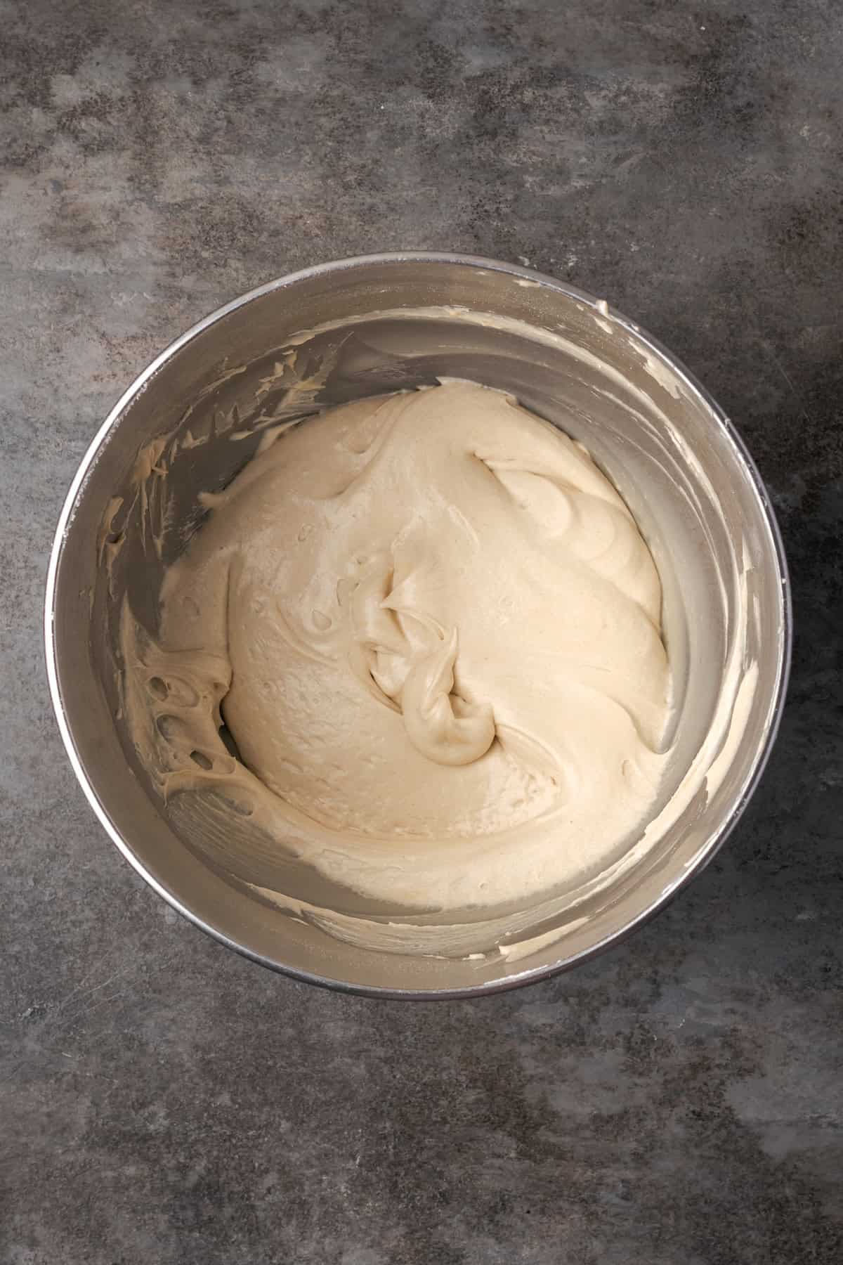 Caramel frosting inside a metal mixing bowl.