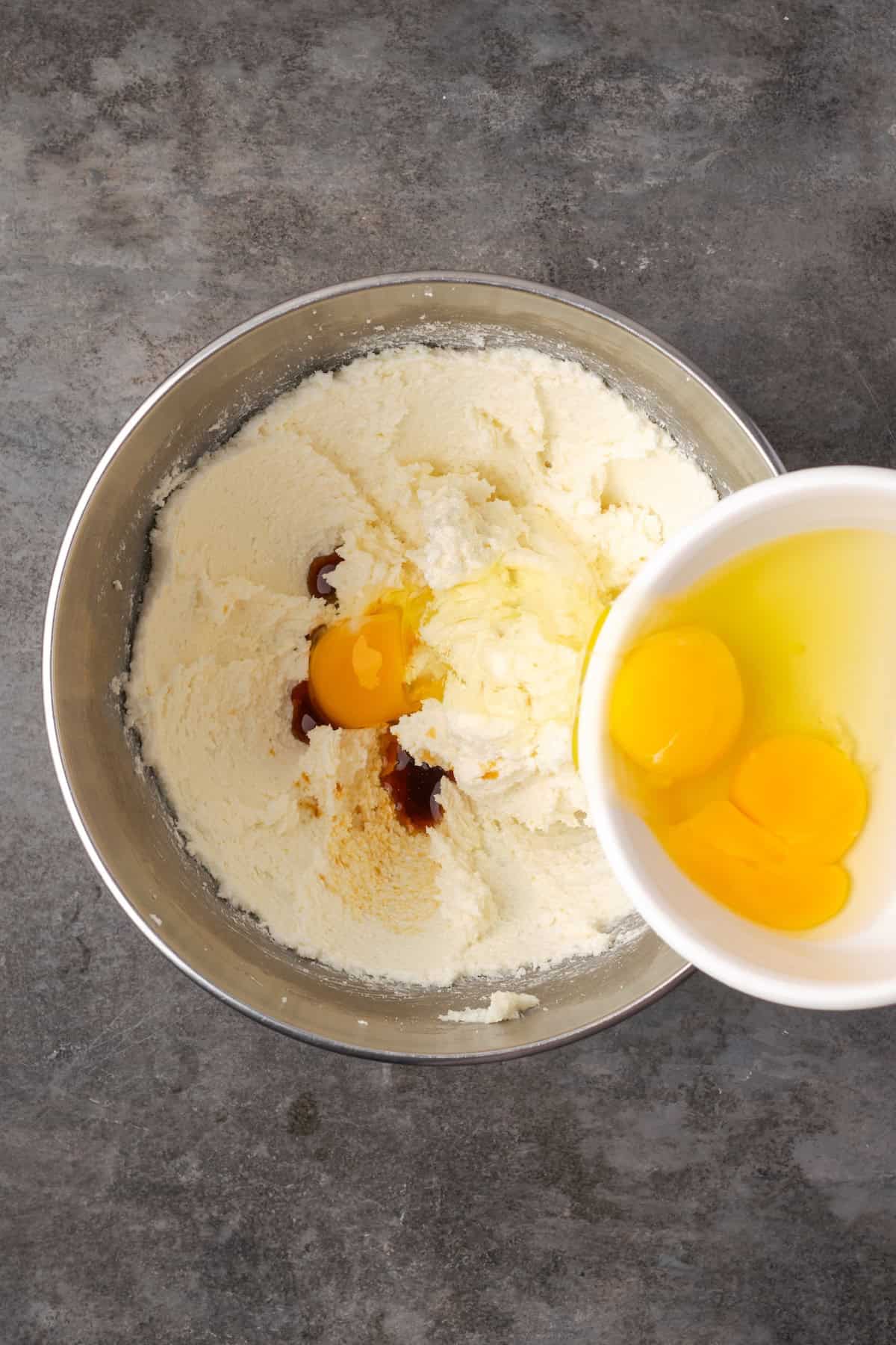 Adding eggs to cupcake batter in a mixing bowl.